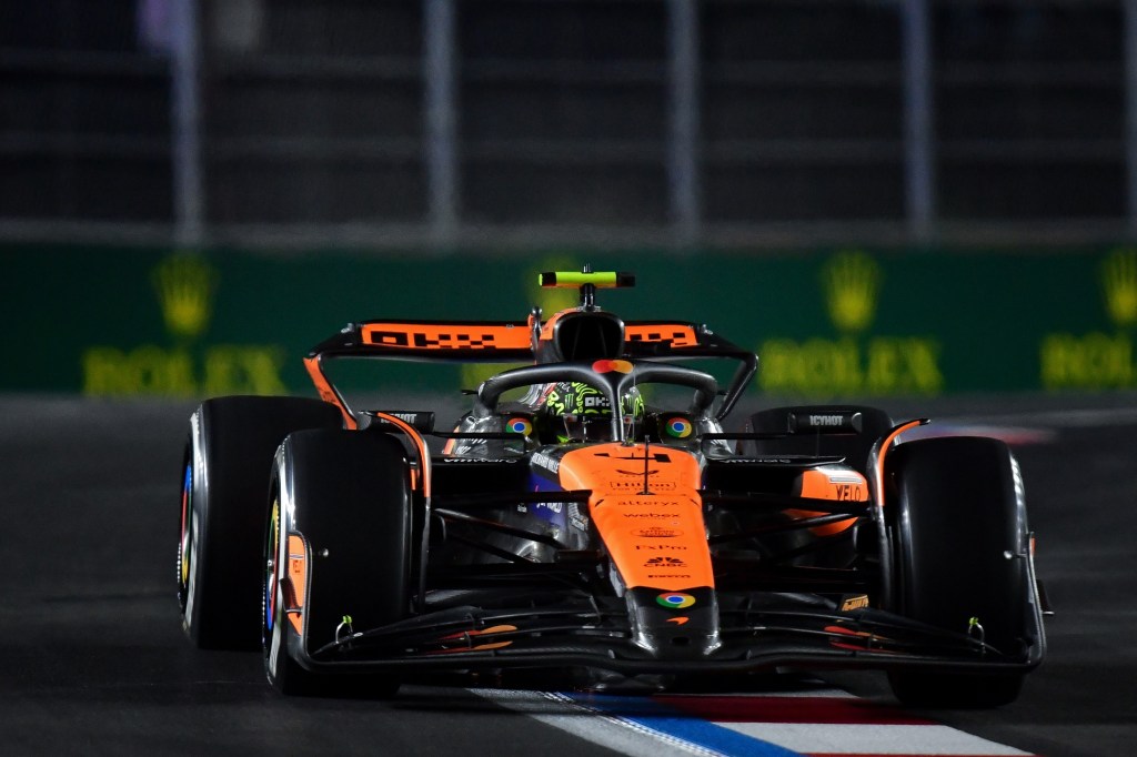 Une voiture de Formule 1 McLaren sur la piste, roulant à haute vitesse avec un éclairage nocturne en arrière-plan.
