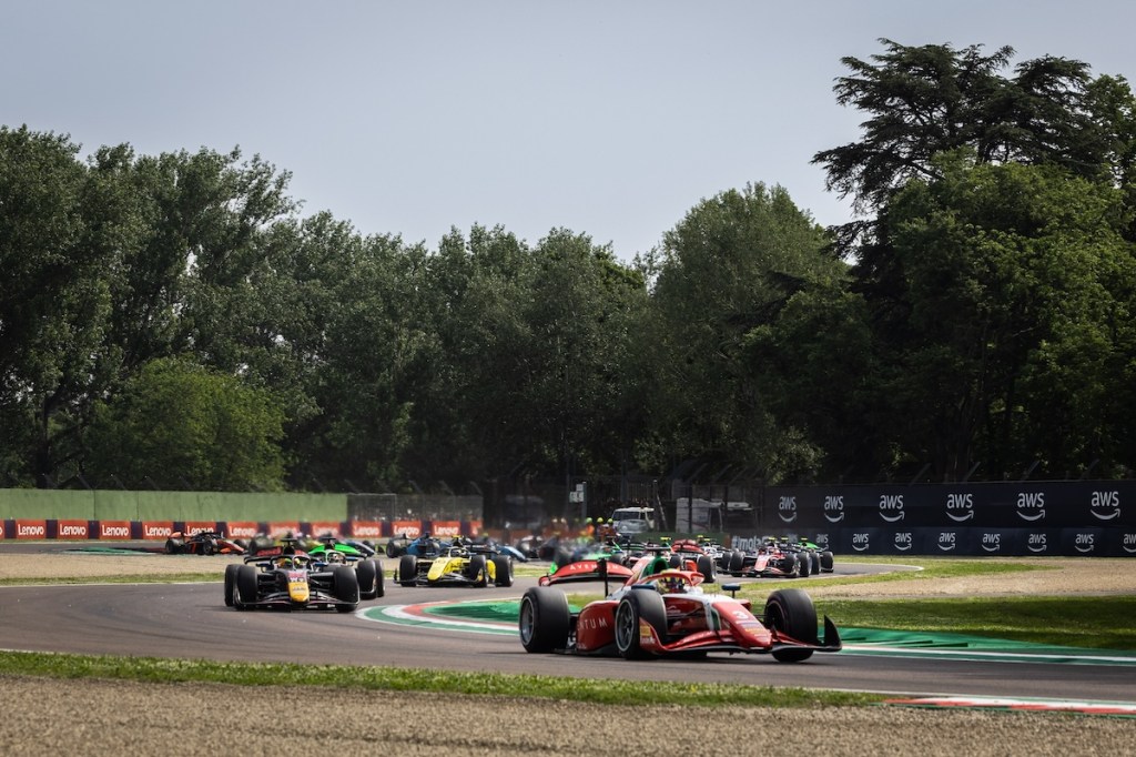 Voitures de course sur le circuit, participant à une compétition de Formule 2, entourées d'une végétation verdoyante.