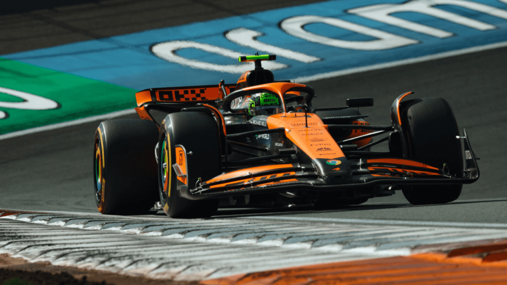 Une voiture de Formule 1 McLaren orange prenant un virage sur un circuit, avec des pneus marqués par l'usure.