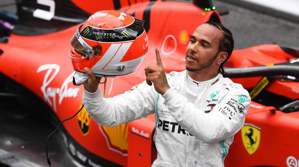 Lewis Hamilton portant son casque de course après le Grand Prix de Monaco 2025, avec une voiture Ferrari en arrière-plan.