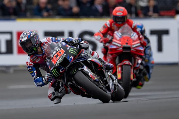 Un pilote de moto de course sur une piste, avec d'autres motos en arrière-plan, lors d'un événement de MotoGP.