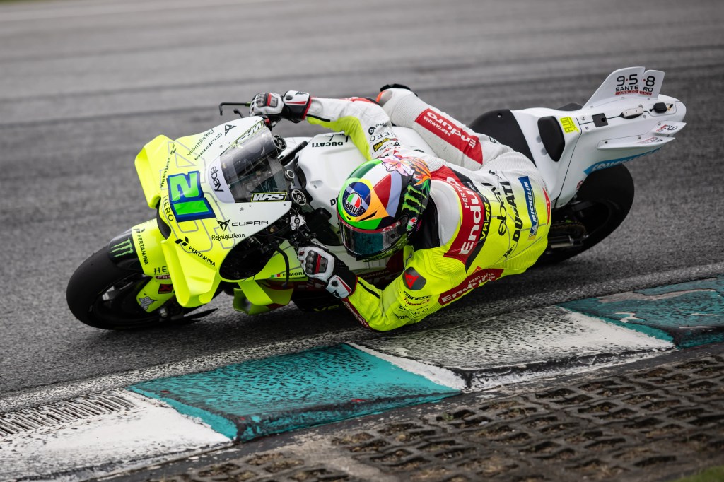 Un pilote de moto avec une combinaison lumineuse effectue une courbe sur une piste de course.