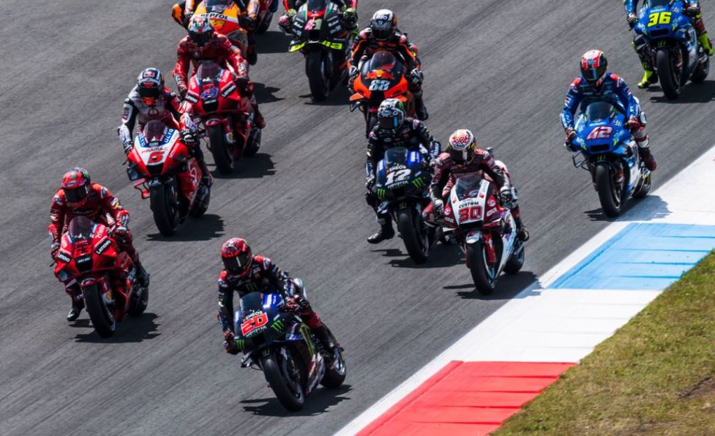 Un groupe de motos de course sur la piste lors d'une session de MotoGP, montrant plusieurs pilotes en compétition sur le circuit d'Assen.