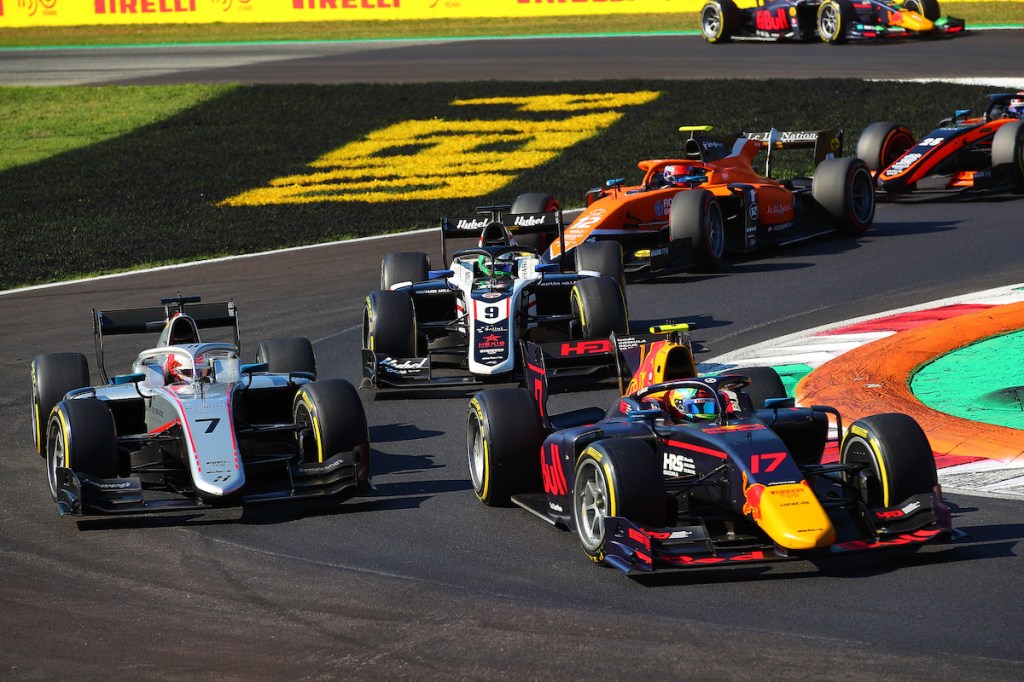 Des voitures de course de Formula 2 et Formula 3 s'affrontent sur une piste, avec des pneus Pirelli visibles en arrière-plan.