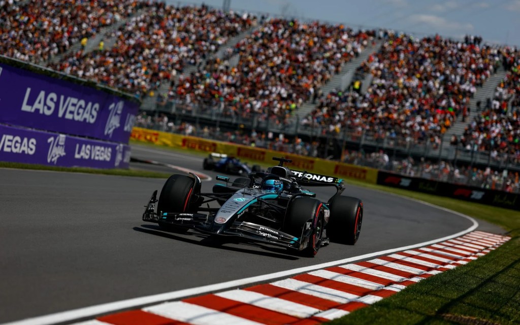 Une voiture de Formule 1 Mercedes en pleine course sur le Circuit Gilles-Villeneuve, entourée de spectateurs dans des conditions estivales.