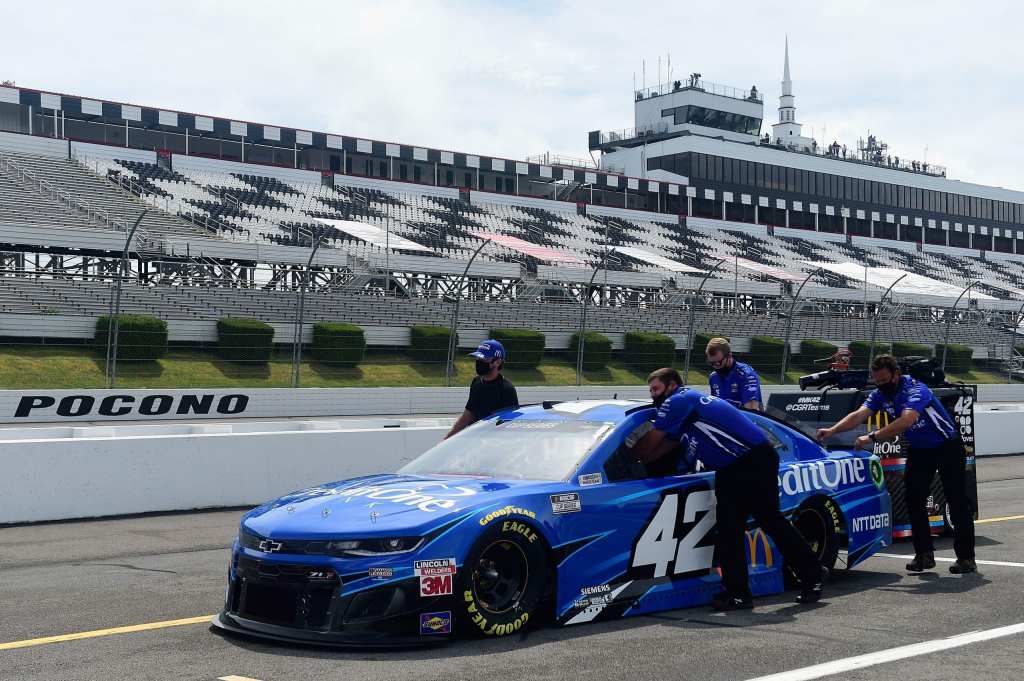 Voiture de course bleue numéro 42 sur la piste de Pocono, avec des membres de l'équipe préparant le véhicule avant la course.