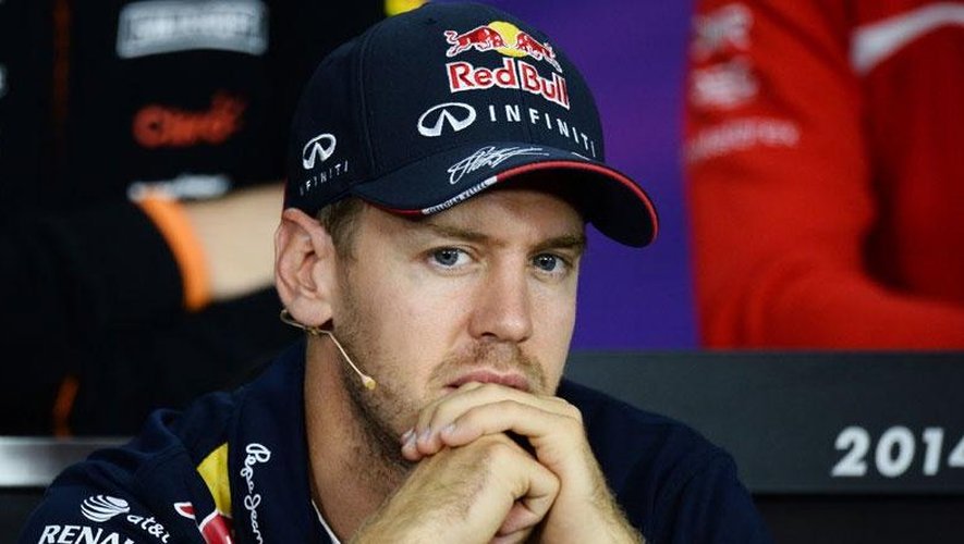 Sebastian Vettel, ancien pilote de F1, avec un regard pensif, portant une combinaison Red Bull et un micro au cou.