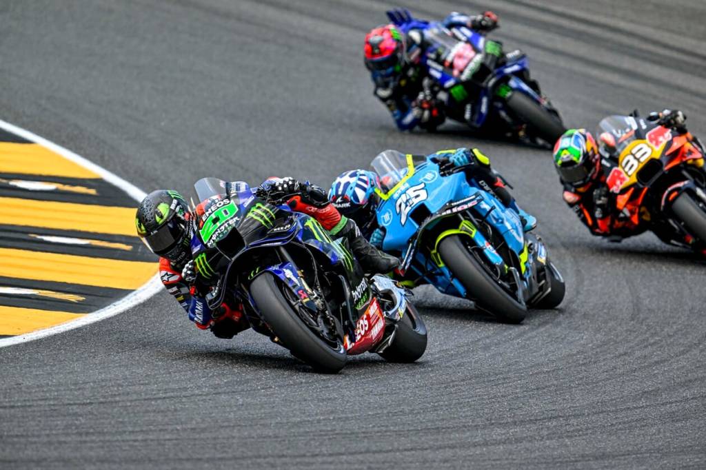 Course de motos sur le circuit, avec plusieurs pilotes en pleine action, tournant à grande vitesse.