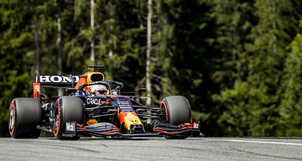 Une voiture de Formule 1 de l'écurie Red Bull Racing sur le circuit Red Bull Ring, entourée de verdure et arbres en arrière-plan.